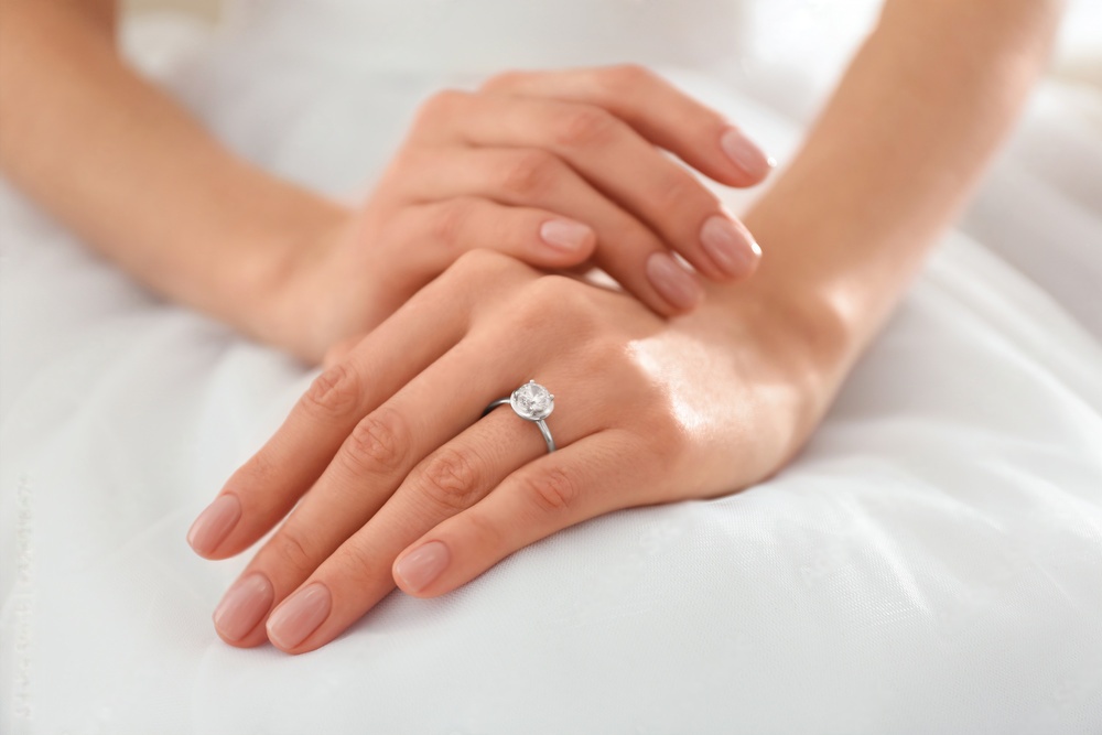 A woman is holding her hands with a diamond ring.